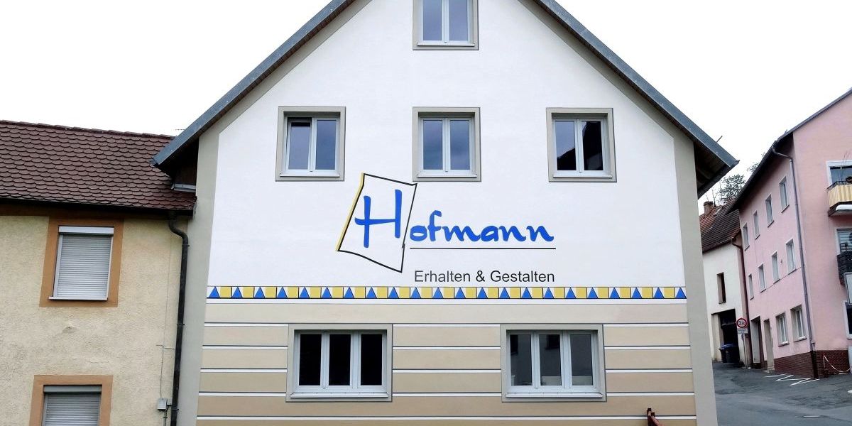 Frontansicht der Werkstatt der Firma mit Bemalung mit dem Logo "Hofmann - Erhalten & Gestalten"